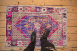 Distressed corner of a vintage Oushak rug with staggered seed motifs and vibrant floral cross-sections.