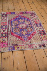 Vibrant floral border on a distressed vintage Oushak rug corner with worn pile.