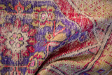 Distressed Oushak rug's folded textile with plum, red, and saffron hues.