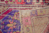 Corner of distressed Oushak rug, showing vibrant fuchsia and purple pile with woven reverse.
