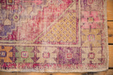 Distressed vintage Oushak rug corner with even wear, saffron seed motif, and pink floral details.