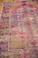 Distressed Oushak rug showing worn pile, vibrant pink, purple, and yellow motifs.