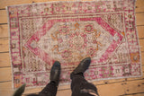 Overall worn texture and faded plum, blue, orange medallion of a vintage Oushak rug.