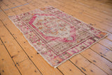 Distressed corner of vintage Oushak rug with faded dusty plum border and visible foundation.