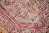 Detailed view of the distressed Oushak rug's dusty plum floral and serpent motifs.