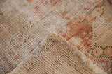 Distressed vintage Oushak rug corner, showing worn beige pile, exposed foundation, and muted copper tones.