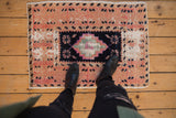 Distressed Oushak rug with stepped diamond medallion in fuchsia, navy, pale red, and ivory.