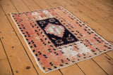 Distressed vintage Oushak rug with navy diamond medallion on a spotted grapefruit red field.