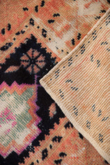Distressed Oushak rug pile detail in fuchsia, navy, and peach, revealing its woven reverse.