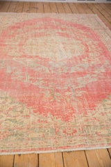 Distressed Oushak rug corner, with pink and ivory border, pile wear, and fringe.