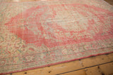 Abrashed pink field and intricate ivory, seafoam green border of distressed Oushak.