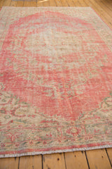 Distressed texture of a vintage Oushak rug, showcasing blush, ivory, and faded green.