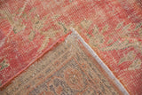 Distressed pink and ivory Oushak rug showing worn pile and geometric hand-knotted reverse.