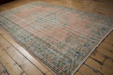 Vintage distressed Oushak carpet showing pale dusty blush field with worn mint green floral vinery.