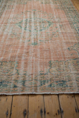 Close-up of distressed Oushak carpet showing worn pile, foundation, pale blush, mint green.