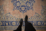 Worn peach field, cobalt blue border, and visible knot heads on this distressed Turkish Oushak carpet.