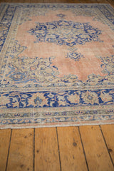 Distressed Oushak rug corner showing cobalt blue border and faded peach field.
