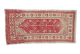 A vintage distressed Oushak runner with a central stemmed plant design in faded raspberry and beige.