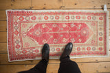 Distressed vintage Oushak runner shown underfoot to demonstrate its scale and worn, low pile.