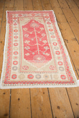 Angled view of a vintage Oushak runner showing its distressed texture and raspberry plant design.