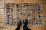 Distressed vintage Turkish Oushak rug with pale brown field, blue pomegranate border, and visible foundation wear.