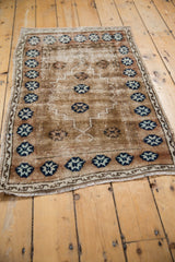 Distressed vintage Oushak rug detail with worn copper field and navy blue pomegranate border.