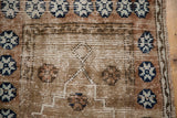 Distressed Oushak rug close-up: worn pile, visible foundation, and muted blue pomegranate motifs.