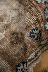 Distressed Oushak rug's textured pile, with brown, ivory, and navy blue wear.