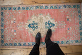 Distressed vintage Oushak runner with faded blush field, navy border, and ivory palmette medallion.