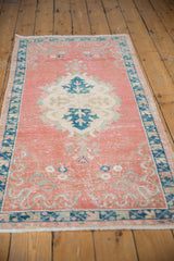 Distressed blush pink vintage Oushak runner, highlighting textured pile and faded blue motifs.
