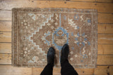 Distressed Oushak rug corner with textured beige, sand, and denim blue design.