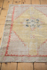 Distressed Oushak rug pile showing dusty gold field and pale brick red stepped border.