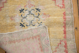 Distressed dusty gold pile and pale red woven foundation of a vintage Oushak rug.