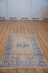 Faded distressed Oushak rug, featuring decorative tangerine, gold, and dusty blue.