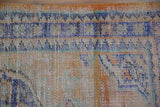 Worn pile texture of the distressed Oushak rug, revealing pale blue, gold, and tangerine orange hues.