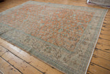 Distressed vintage Oushak rug's pale terra cotta field with scrolling aqua floral vinery.