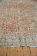 Distressed Oushak carpet detail: terracotta field with blue floral vinery, worn pile, and fringe.