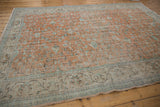 Distressed Oushak carpet's pale terra cotta field, scrolling vinery, and ivory meandering vine border.
