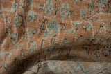 Distressed vintage Oushak pile, showing pale terra cotta, ivory, and dusty teal floral designs.