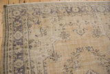 Faded floral motifs on distressed Oushak rug corner with visible knot head wear.