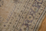 Distressed Oushak border, worn to knot heads, in muted beige, green, and blue tones.