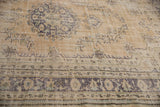 Distressed Oushak carpet: beige, ivory, dusty blue border, geometric motifs, visible wear.