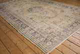 Distressed Oushak rug corner showing faded floral border, mostly even wear, and intact selvage.