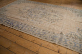 Distressed vintage Oushak carpet's muted denim blue and ivory tones in the border.