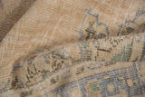 Textured pile of distressed vintage Oushak rug, showing muted beige, ivory, and denim blue.