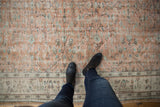Distressed vintage Oushak rug showing textural pale terracotta and mint green floral vinery.
