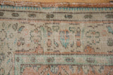 Distressed Oushak rug texture: worn knot heads, visible foundation, ivory, terracotta, mint green.