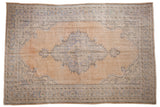 Distressed vintage Oushak rug, faded apricot and blue tones, scalloped medallion, abrashed field.