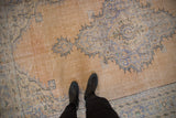 Vintage distressed Oushak carpet with abrashed apricot field and faded blue scalloped medallion pattern.