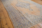 Distressed vintage Oushak rug with scalloped medallion, trefoil finials, and abrashed apricot field.